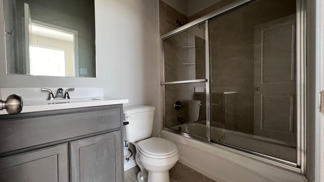 full bathroom featuring toilet, bath / shower combo with glass door, and vanity