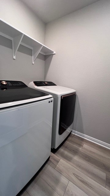 clothes washing area with hardwood / wood-style flooring and washing machine and clothes dryer