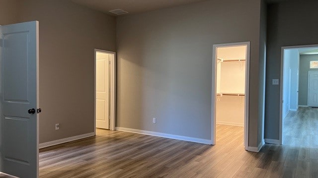 unfurnished bedroom featuring a spacious closet, dark wood-type flooring, and a closet