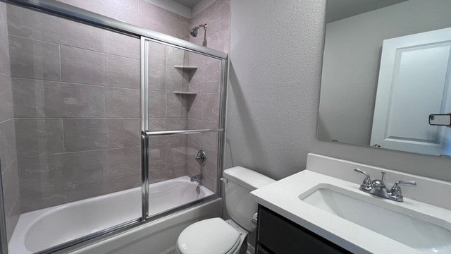 full bathroom with vanity, toilet, and bath / shower combo with glass door