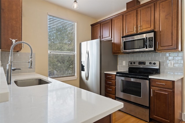 kitchen featuring appliances with stainless steel finishes, tasteful backsplash, sink, and light hardwood / wood-style floors