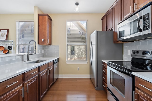 kitchen with light hardwood / wood-style flooring, decorative backsplash, stainless steel appliances, and sink