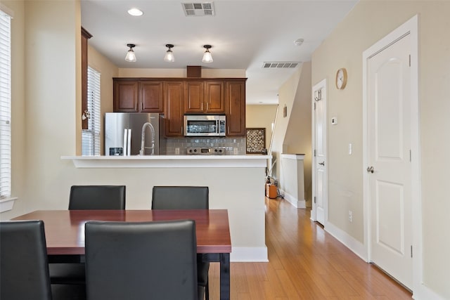 kitchen featuring decorative backsplash, appliances with stainless steel finishes, light wood-type flooring, and plenty of natural light