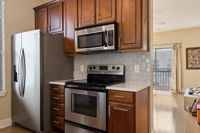 kitchen with backsplash, stainless steel appliances, and light hardwood / wood-style floors