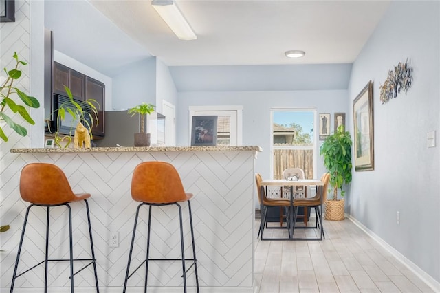 bar with vaulted ceiling and light stone counters