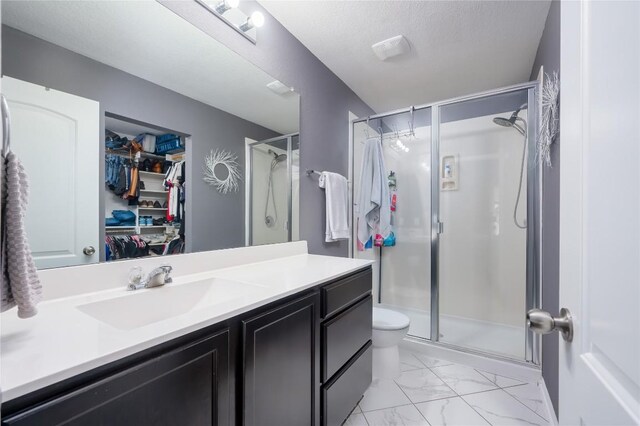 bathroom with a textured ceiling, vanity, an enclosed shower, and toilet