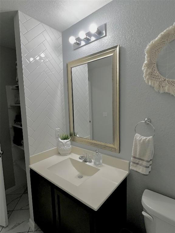 bathroom with vanity, a textured ceiling, and toilet