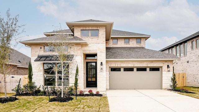 prairie-style home featuring a shingled roof, stone siding, fence, and driveway