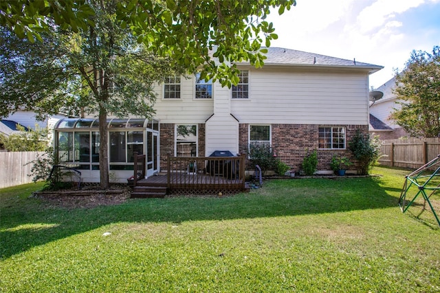 rear view of property with a wooden deck, a sunroom, and a lawn