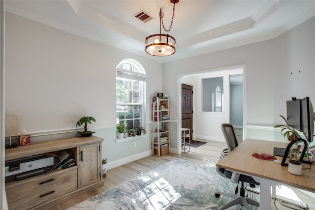 office area featuring ornamental molding, light hardwood / wood-style flooring, and a tray ceiling