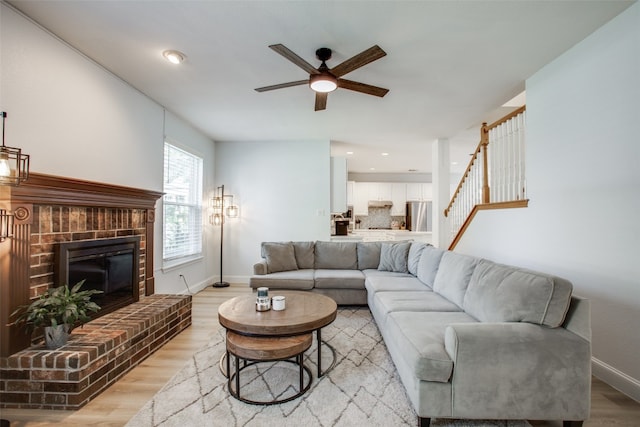 living room featuring a fireplace, light hardwood / wood-style floors, and ceiling fan