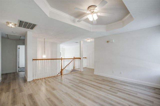 spare room featuring ornamental molding, ceiling fan, light hardwood / wood-style floors, and a raised ceiling