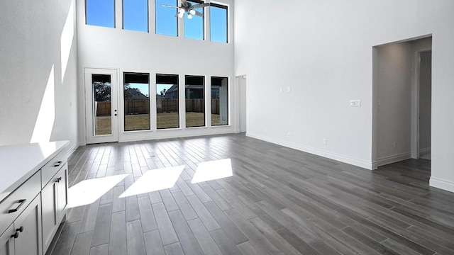 120 Teakmill Trl, San Marcos, TX 78666 - unfurnished living room featuring a ceiling fan, dark wood-style flooring, a towering ceiling, and baseboards