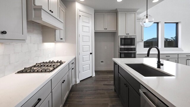 kitchen with pendant lighting, sink, stainless steel appliances, dark hardwood / wood-style flooring, and decorative backsplash