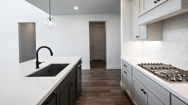 kitchen featuring sink, backsplash, dark hardwood / wood-style floors, decorative light fixtures, and stainless steel gas stovetop