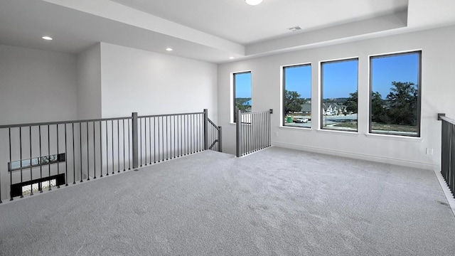 spare room featuring a tray ceiling and carpet