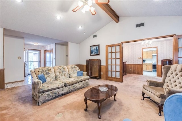 living room featuring light carpet, beamed ceiling, visible vents, and wainscoting