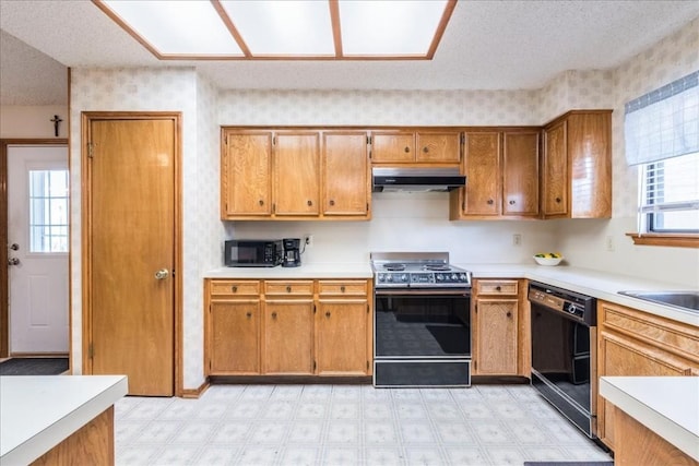 kitchen with under cabinet range hood, light floors, brown cabinets, plenty of natural light, and black appliances