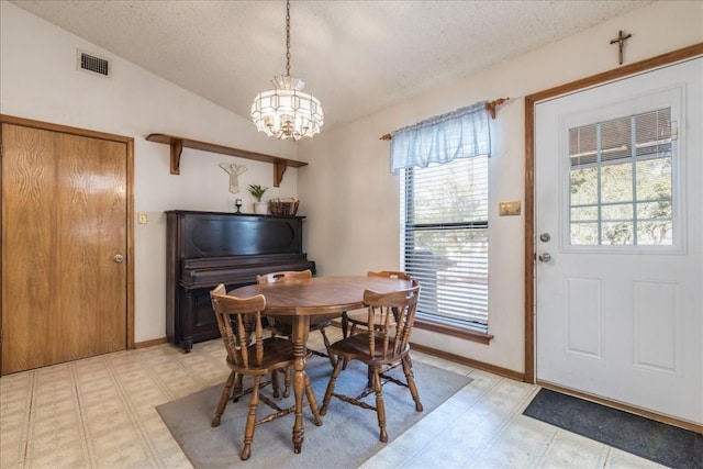 dining area featuring visible vents, light floors, a chandelier, and vaulted ceiling