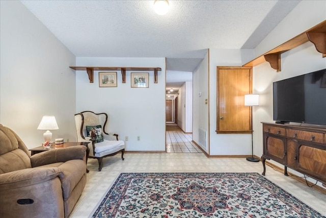 living room with visible vents, baseboards, a textured ceiling, and light floors