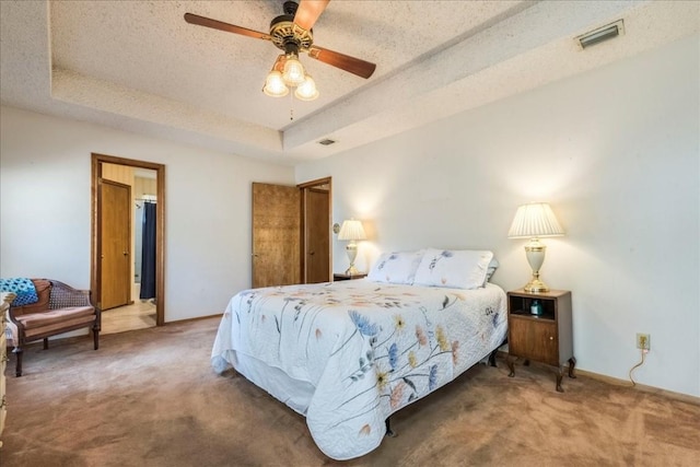 bedroom featuring visible vents, a textured ceiling, carpet, and a tray ceiling