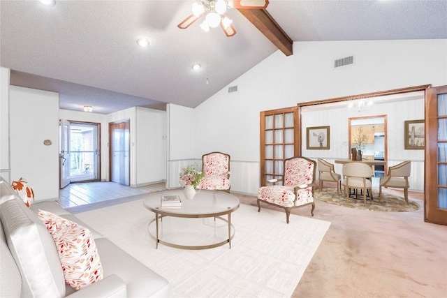 living area featuring visible vents, vaulted ceiling with beams, ceiling fan, and carpet floors