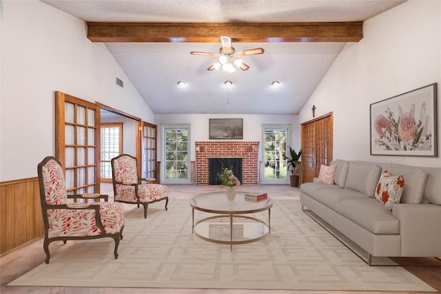 living room featuring beam ceiling, visible vents, light colored carpet, and a textured ceiling