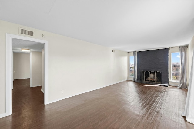 unfurnished living room featuring a brick fireplace and dark hardwood / wood-style floors