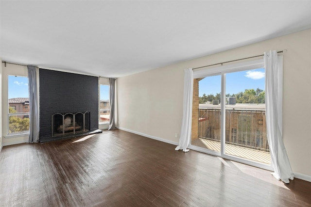 unfurnished living room featuring a brick fireplace, wood-type flooring, and a healthy amount of sunlight