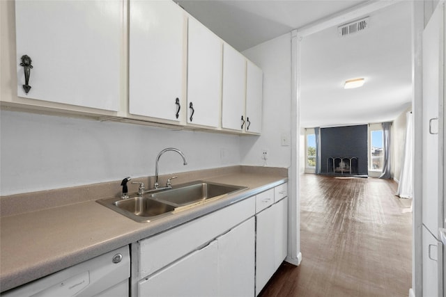 kitchen with dark wood-type flooring, white dishwasher, sink, and white cabinets