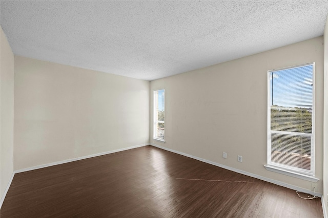 spare room with a textured ceiling and dark hardwood / wood-style floors