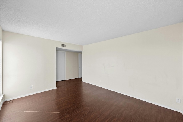 unfurnished room with dark wood-type flooring and a textured ceiling