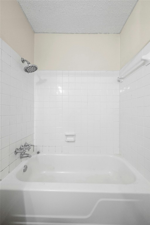 bathroom with tiled shower / bath and a textured ceiling