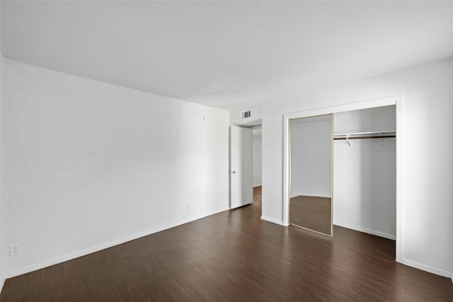 unfurnished bedroom featuring a closet and dark wood-type flooring