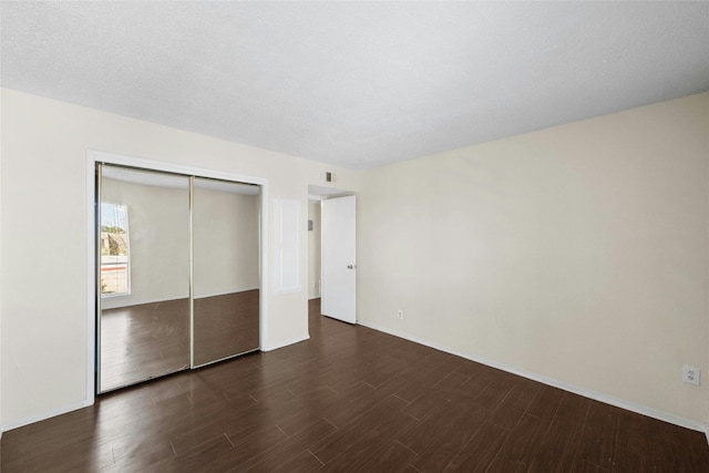 unfurnished bedroom featuring dark wood-type flooring, a textured ceiling, and a closet