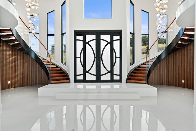 entrance foyer featuring a high ceiling, a notable chandelier, and wooden walls