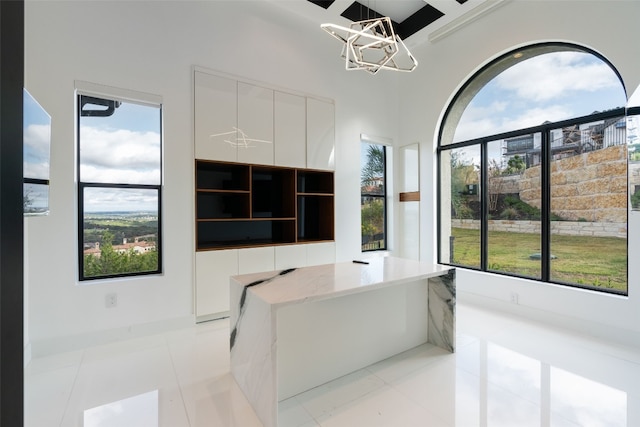 kitchen featuring white cabinetry, light stone countertops, hanging light fixtures, and light tile patterned floors