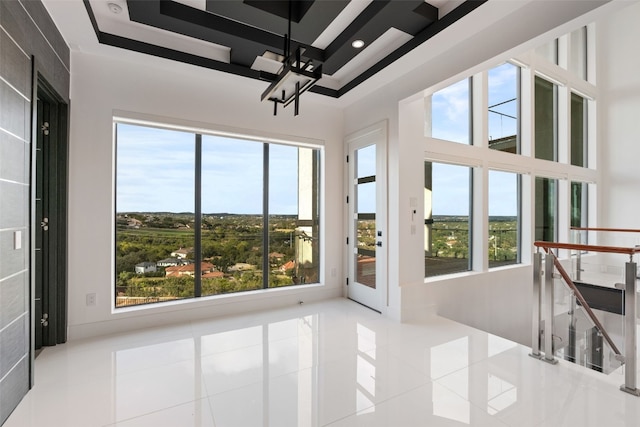 unfurnished sunroom with an inviting chandelier, a healthy amount of sunlight, and a raised ceiling