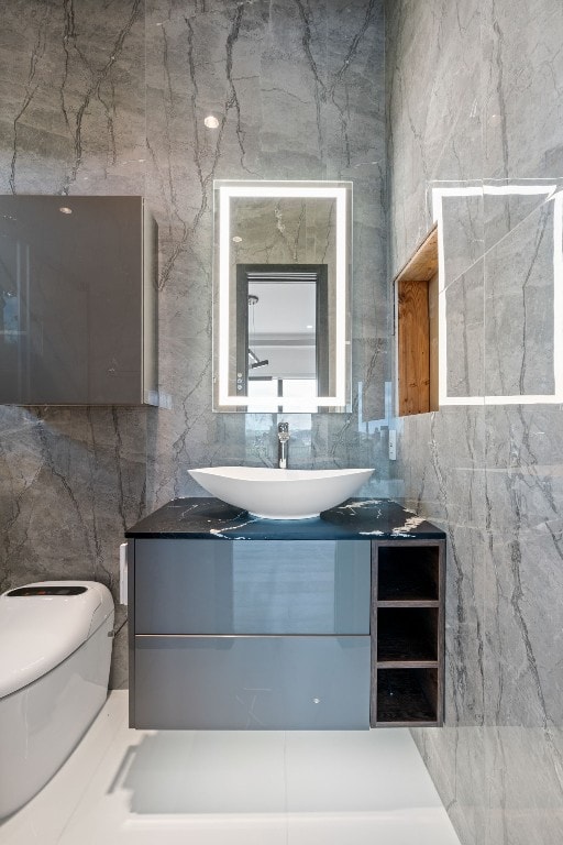 bathroom with tile walls, vanity, and toilet