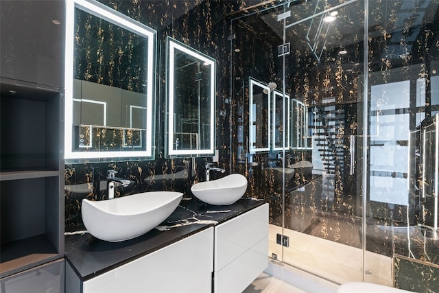 bathroom featuring vanity, a shower with shower door, and tile walls