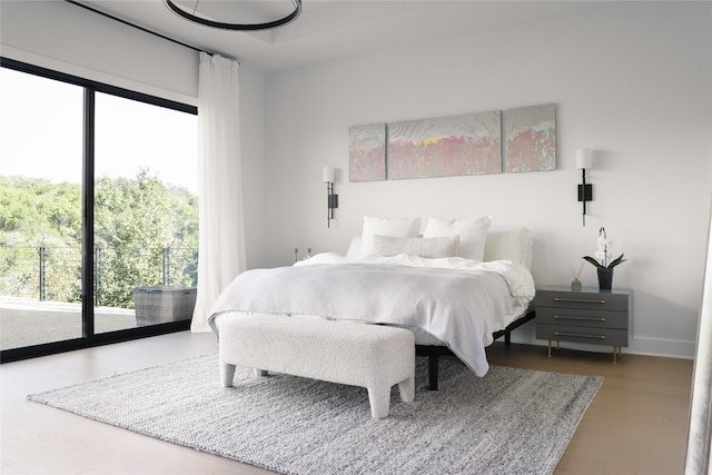 bedroom featuring multiple windows, wood-type flooring, and access to exterior