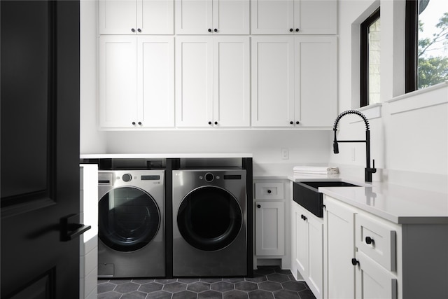 washroom featuring cabinets, washing machine and dryer, dark tile patterned floors, and sink