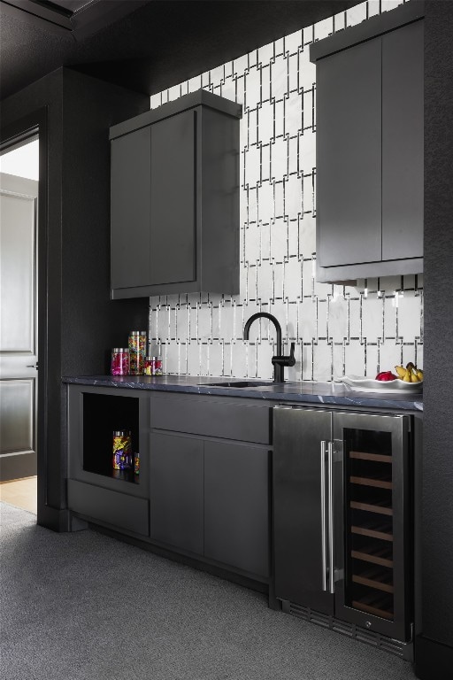 bar with sink, beverage cooler, tasteful backsplash, gray cabinets, and light carpet