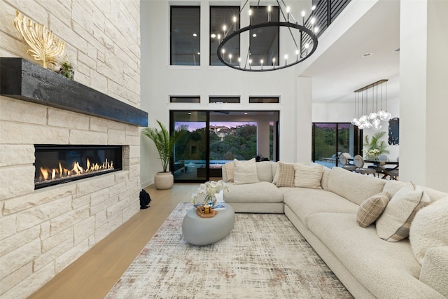 living room featuring plenty of natural light, a stone fireplace, a high ceiling, and light hardwood / wood-style flooring