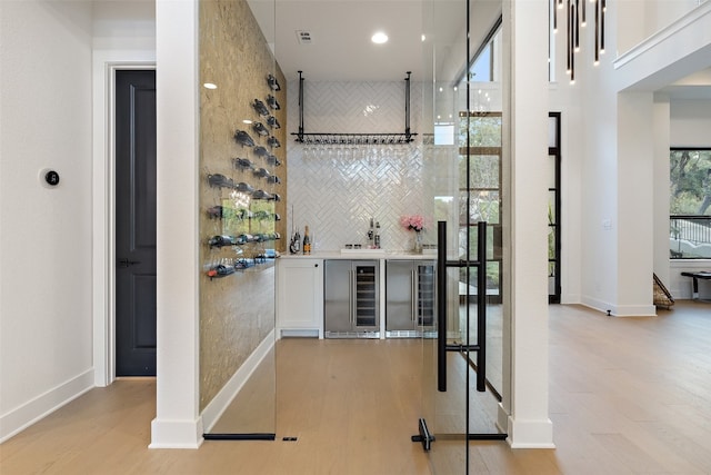 bar featuring white cabinetry, light hardwood / wood-style flooring, and beverage cooler