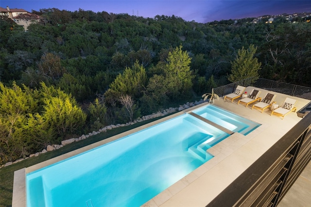 pool at dusk with a patio area