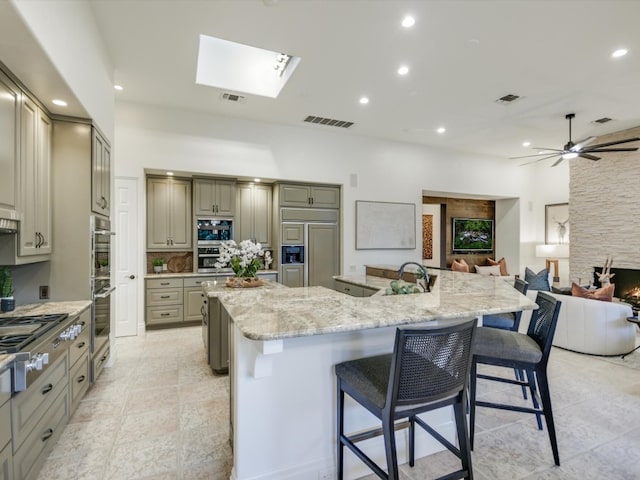 kitchen featuring a spacious island, appliances with stainless steel finishes, a kitchen bar, and a fireplace