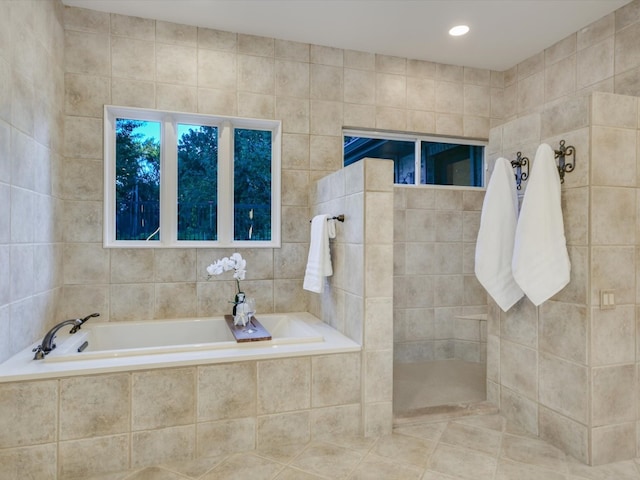 bathroom with tile walls and independent shower and bath