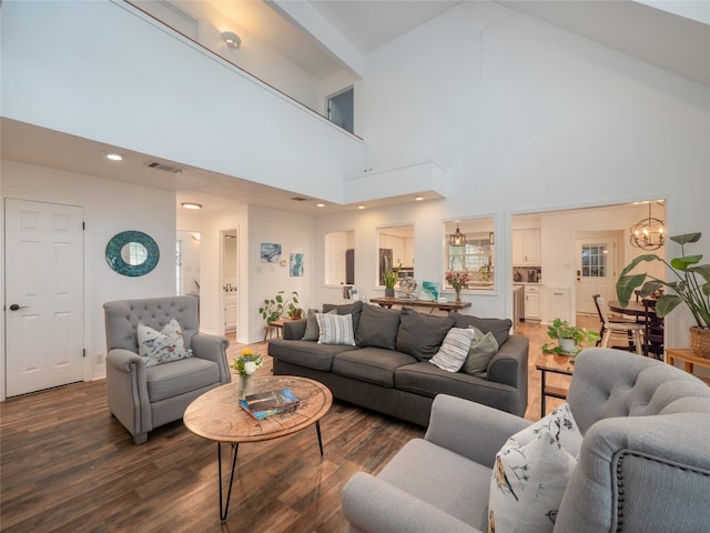 living room with dark hardwood / wood-style flooring, high vaulted ceiling, and an inviting chandelier