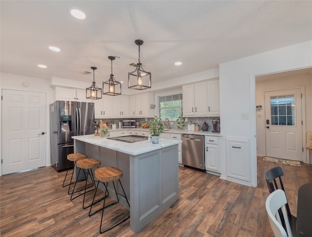 kitchen with pendant lighting, a center island, dark hardwood / wood-style flooring, white cabinetry, and stainless steel appliances